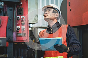 Asian engineer working inspection machine equipment at a factory