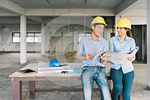 Asian engineers couple working together on building blueprint at construction site or factory. Construction engineering concept