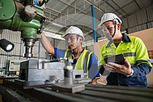 Asian engineers working with worker wearing safety goggles working at lathe. Safety first concept