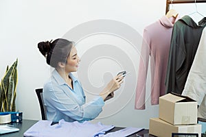 Asian entrepreneur is checking the remaining clothes in her warehouse via her tablet