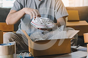 Asian entrepreneur teenager is carrying baby shoes and put in a cardboard box customer to deliver the product at home