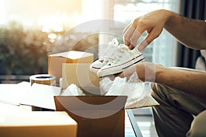 Asian entrepreneur teenager is carrying baby shoes and put in a cardboard box customer to deliver the product at home