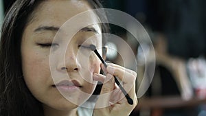 Asian ethnic woman do her own eye shadow make up in slow moiton