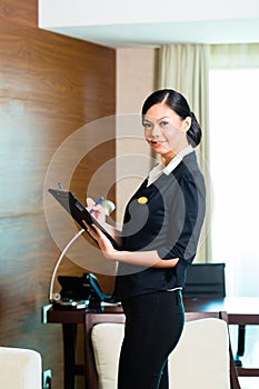 Asian executive housekeeper controlling hotel room