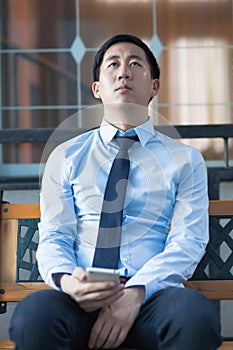 Asian exhausted businessman sitting in corporate building