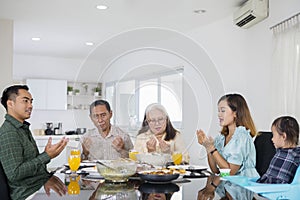 Asian extended family prays together before meals