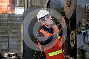 Asian factory worker or technician man with safety uniform check and maintenance machine in factory workplace area. Concept of