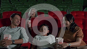 An Asian family audience enjoys watching cinema together at movie theaters.