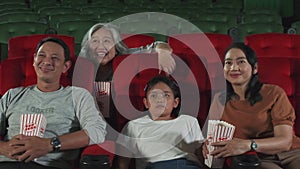 An Asian family audience enjoys watching cinema together at movie theaters.