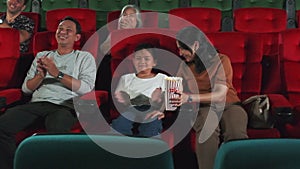 An Asian family audience enjoys watching cinema together at movie theaters.