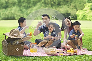 Asian family blows bubble soap in the park