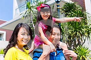 Asian family with child standing in front of home