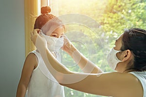 Asian family with children in face mask, mother prepare to put face mask on her kid before leaving house to go school for prevent
