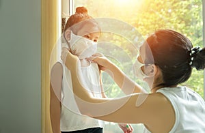 Asian family with children in face mask, mother prepare to put face mask on her kid before leaving house to go school for prevent