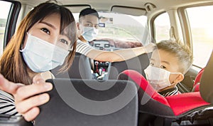 Asian family with children rides in their car and wear medical masks