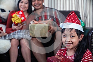 Asian family in Christmas interior.Happy daughter mother and father holding a gift box with smile