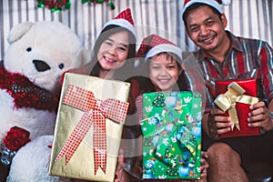 Asian family in Christmas interior.Happy mother father and  daughter holding a gift box with smile