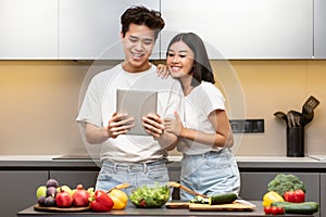 Asian Family Couple With Digital Tablet Cooking Together In Kitchen