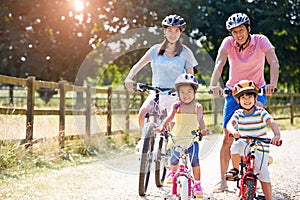 Asian Family On Cycle Ride In Countryside