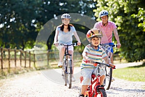 Asian Family On Cycle Ride In Countryside