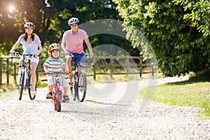 Asian Family On Cycle Ride In Countryside