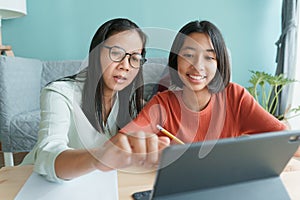 Asian family with a daughter do homework by using tablet with mother help. Happy smile Asia kid while sitting in the living room