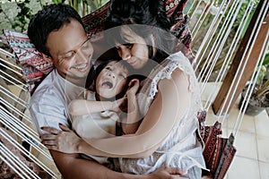 Asian family with daughter while relax on hammock