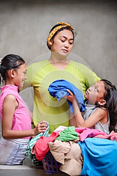 Asian Family Domestic Lifestyle. Stay at Home Mother Doing Laundry Disturbed by Her Children