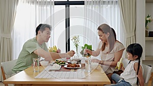 Asian family eating breakfast at the dining table inside the kitchen, family relationships