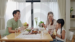 Asian family eating breakfast at the dining table inside the kitchen, family relationships