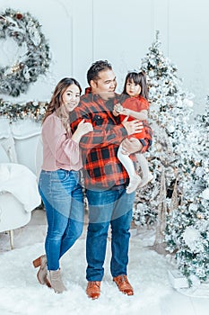 Asian family father dad hugging with daughter toddler girl celebrating Christmas or New Year. Mixed race dad man with kid standing