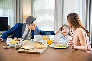 Asian family father, mother with children daughter eating breakfast food on dining table kitchen in mornings