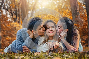 Asian family, father, mother and daugther having goodtime together in park in autumn season photo