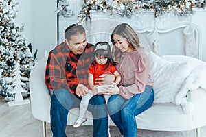 Asian family father, mother giving gift box with present to daughter toddler girl celebrating Christmas or New Year