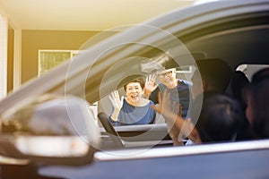 Asian family of father, mother and son waving goodbye to grandfather and grandmother as they take off their journey.