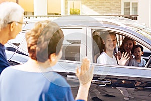 Asian family of father, mother and son waving goodbye to grandfather and grandmother as they take off their journey.