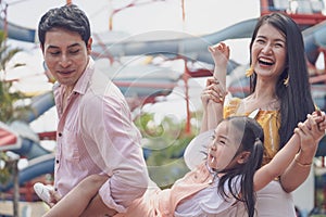 Asian family father mother and young daughter playing together at amusement park. concept family outing at the playground vacation