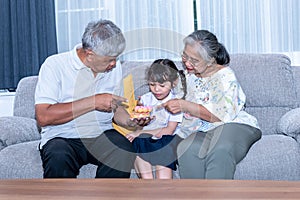 Asian family, Grandpa and elderly grandmother, persuading granddaughter to eat a snack, is sweet donut photo