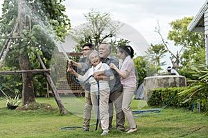 Asian family haapy with smil lovely are watering a tree by tube in garden at outdoor house in morning