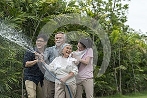 Asian family haapy with smil lovely are watering a tree by tube in garden at outdoor house in morning