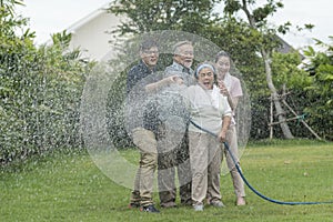 Asian family is haapy with smil lovely are watering a tree by tube in garden at outdoor house in morning