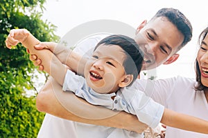 Asian family having fun and carrying a child in public park.