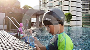 Asian Family is having fun swimming together in Hotels swimming pool in Vacation trip.