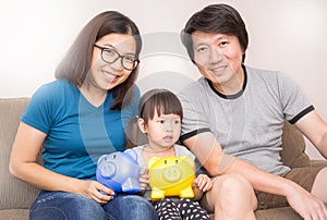 Asian family holding piggy bank in the living room