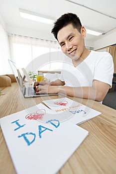 Asian family I love you, dad! Father and son together happy design a Father`s Day card with a computer on the bed at home.Concept