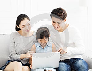 Asian family with laptop on sofa