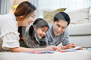 Asian family lying on floor painting with little child daughter in living room