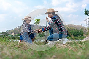 Asian family mom and kid daughter plant sapling tree outdoors in nature spring for reduce globa