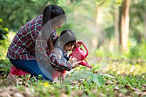 Asian family mom and kid daughter plant sapling tree outdoors in nature spring for reduce global warming growth feature