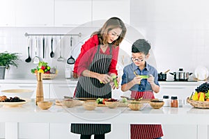 Asian family mom in red shirt and black apron is teaching her s